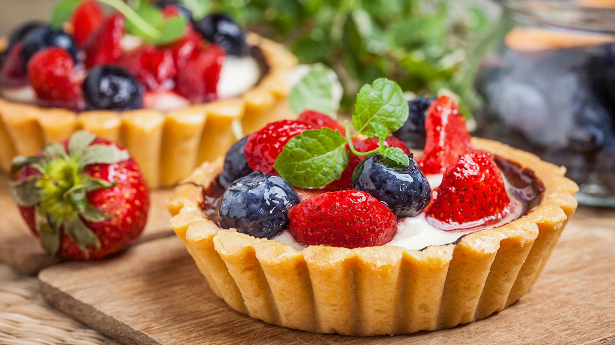 Berry tarts with strawberries and blueberries on a wooden board, Paris Saint Germain food tour.