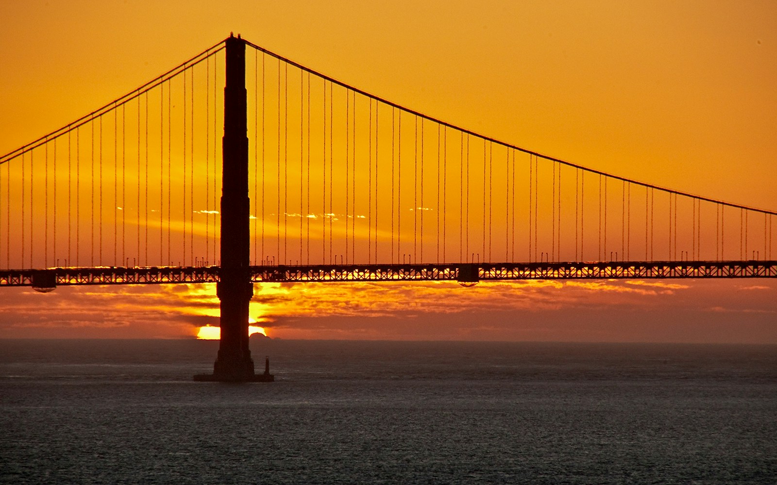 Golden Gate Bridge silhouetted against sunset, view from Alcatraz, San Francisco.