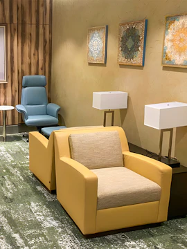 Seating area in Plaza Premium Lounge Jeddah with armchairs and wall art.