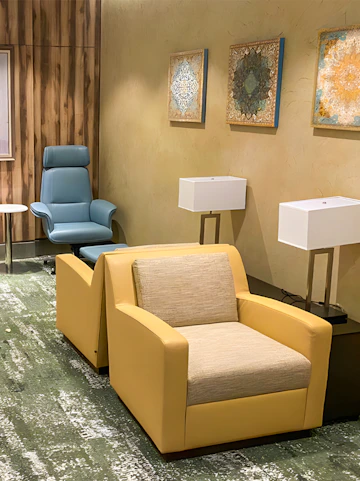 Seating area in Plaza Premium Lounge Jeddah with armchairs and wall art.