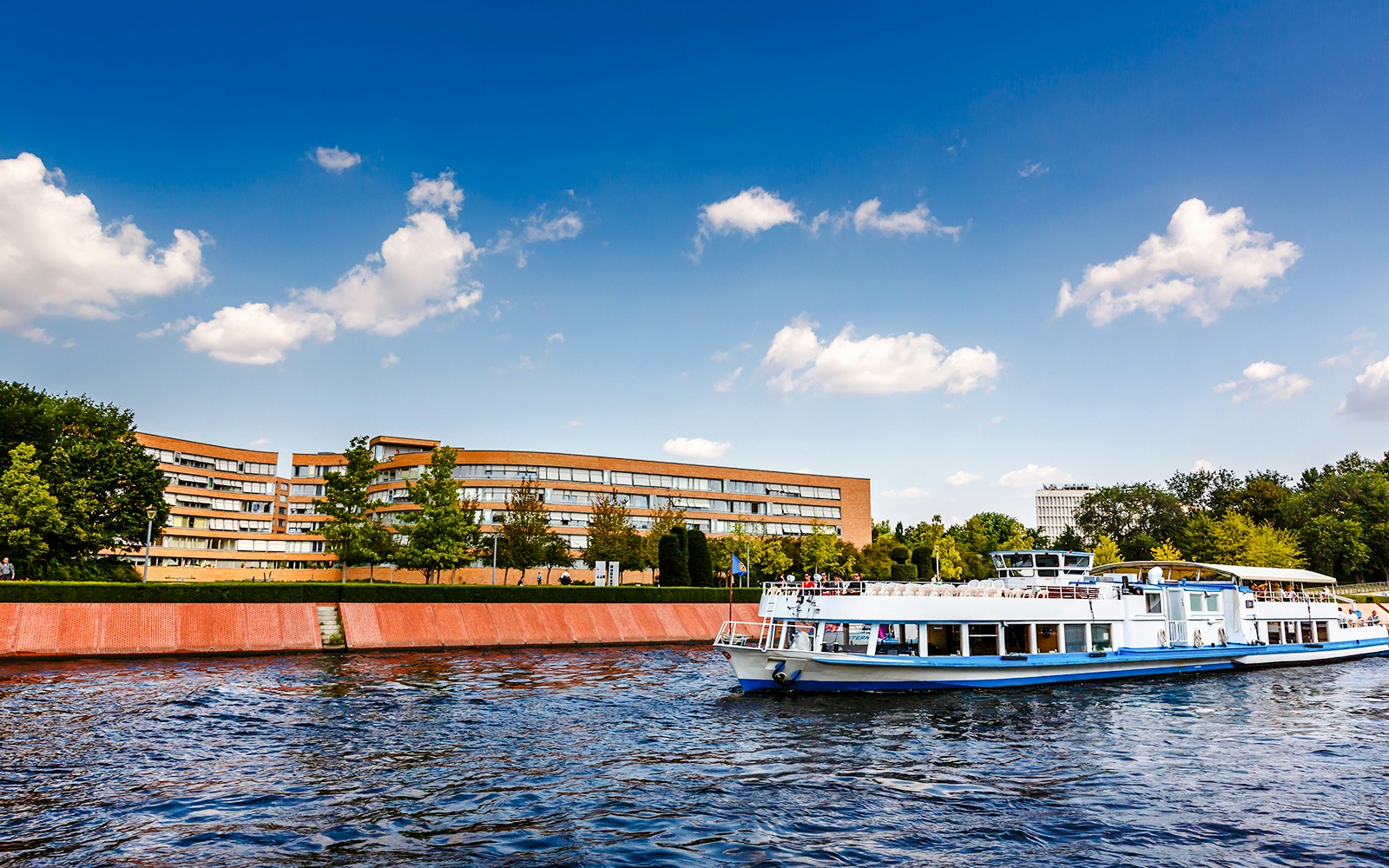 Boat cruising on the Spree River with modern buildings in Berlin, Germany.