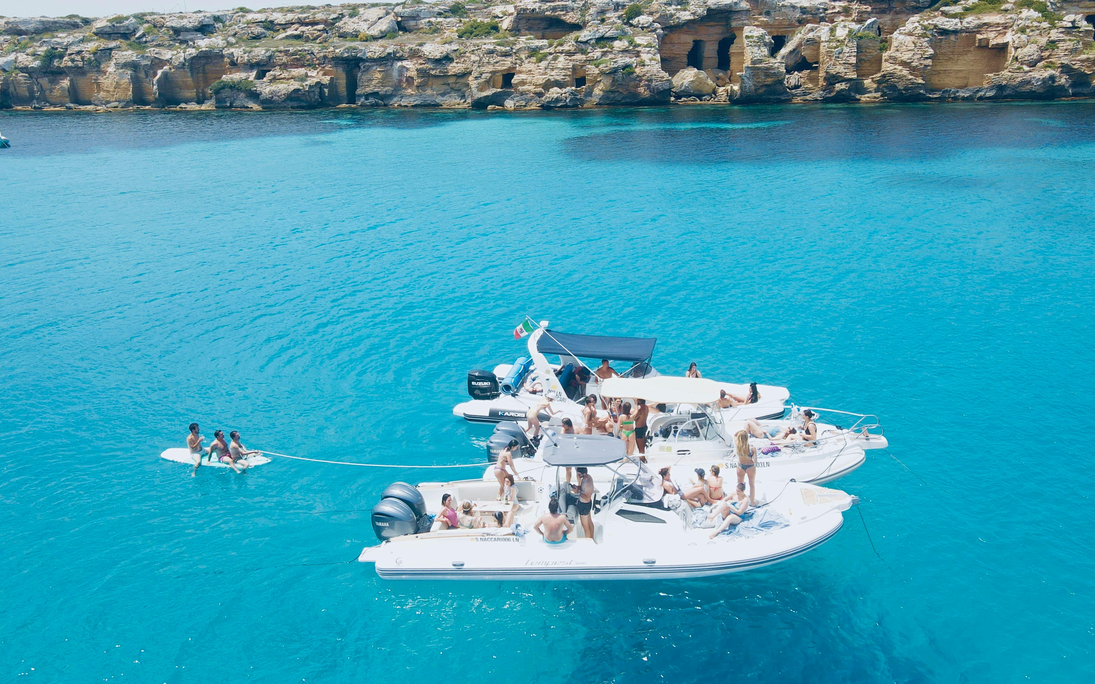 Boat tour with people enjoying the sea near rocky coastline of Favignana and Levanzo.