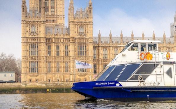 Cruise boat on the Thames by Westminster Palace in London.