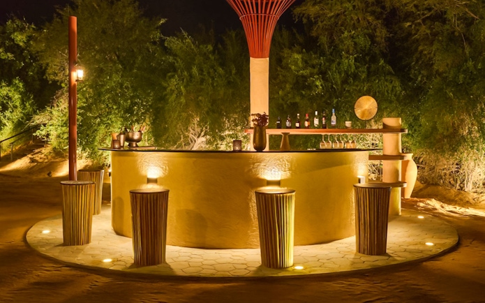 Bar counter at The Nomad Garden, a premium desert dining experience, with stools and ambient lighting.