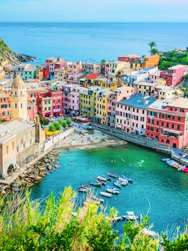 Colorful buildings and boats in Vernazza, Cinque Terre, viewed from above, with the sea in the background.