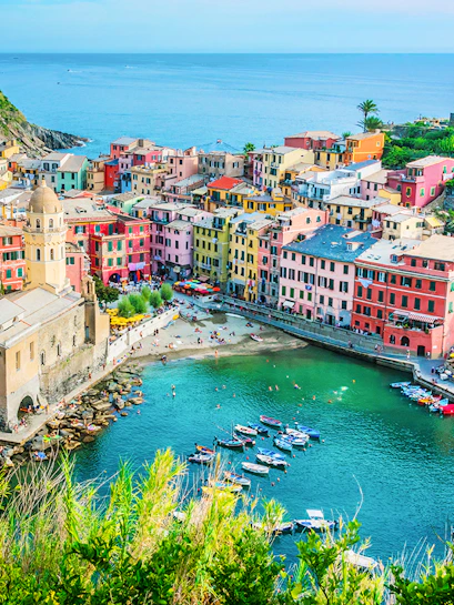 Colorful buildings and boats in Vernazza, Cinque Terre, viewed from above, with the sea in the background.