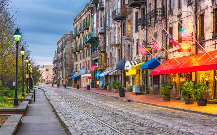 Historic River Street in Savannah with colorful storefronts and cobblestone path.