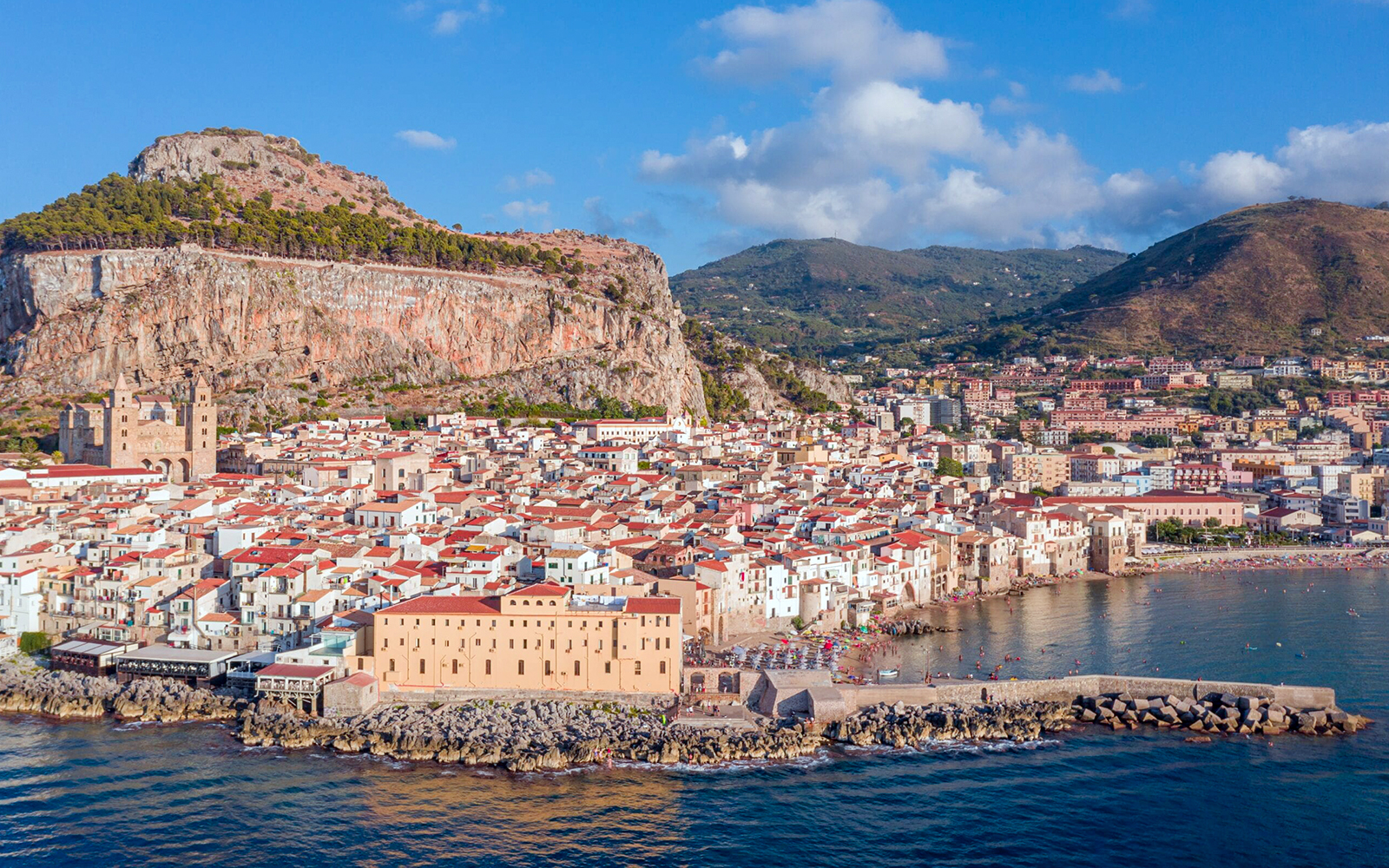 Aerial view of Palermo's coastline with historic buildings and mountains.