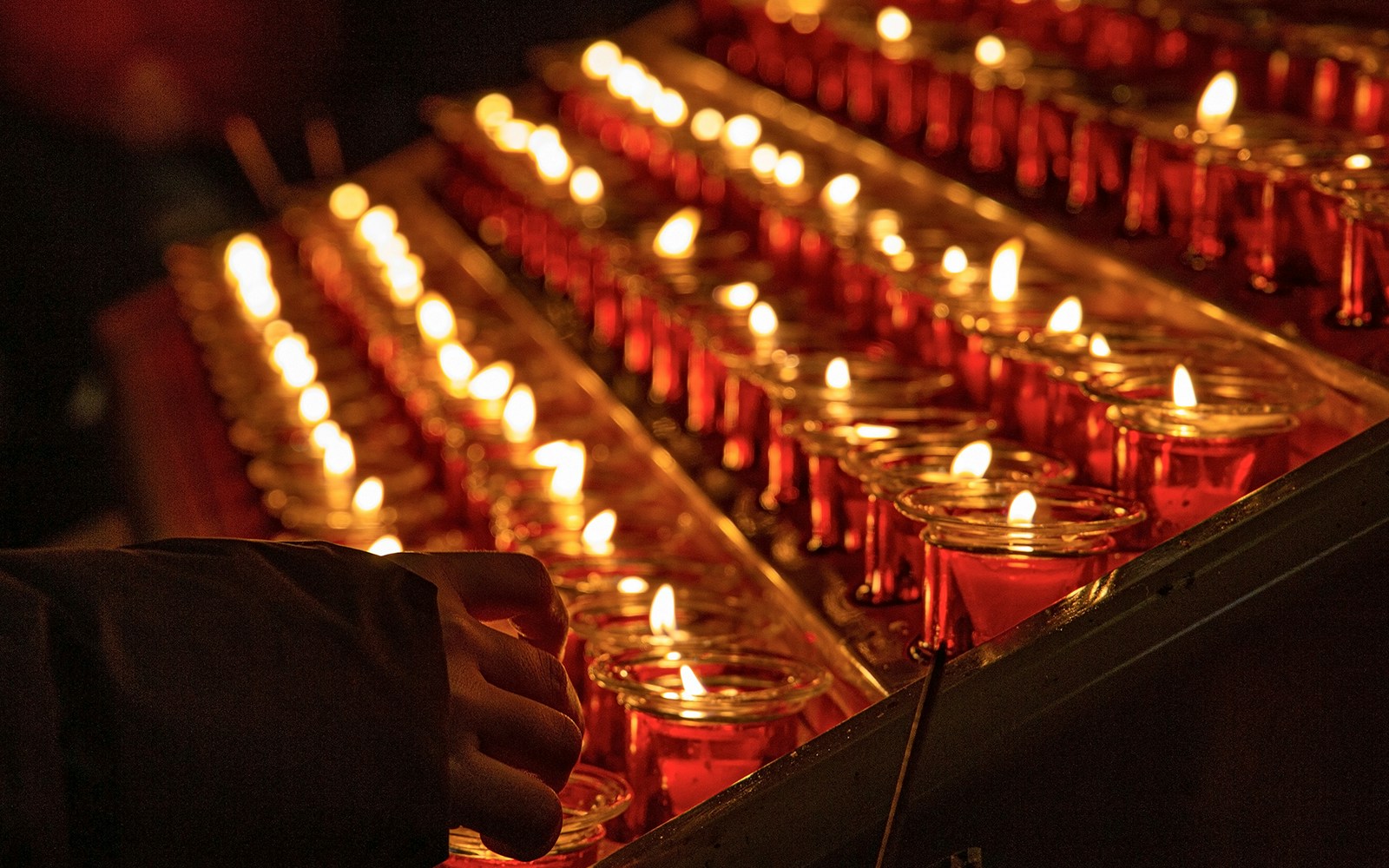 Woman lighting candlesticks in a historic church, enhancing a spiritual tour experience in Europe.