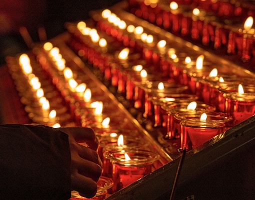 Woman lighting candlesticks in a historic church, enhancing a spiritual tour experience in Paris.
