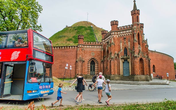 Krakow hop-on hop-off bus near Kościuszko Mound with tourists exploring the area.