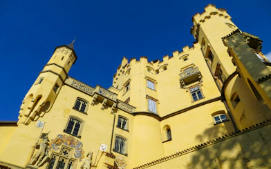 Hohenschwangau Castle facade with towers under clear blue sky, Bavaria.