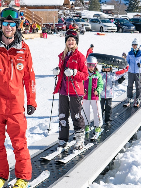 Beginner skiers on a conveyor lift in Grindelwald during a full-day ski package from Interlaken.
