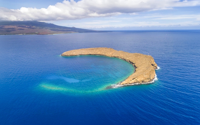 Molokini Crater in Maui, Hawaii surrounded by blue ocean waters.