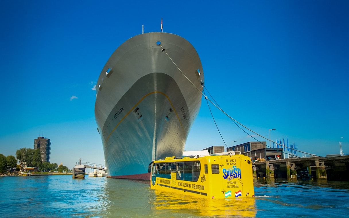 Amphibious bus on Rotterdam waterway near large ship during 1-hour sightseeing splash tour.