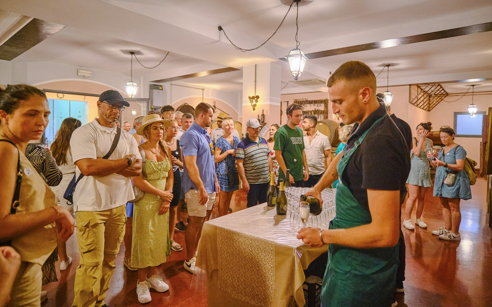 Tourists enjoying a wine tasting experience in Tuscany during a Pisa, Siena, and San Gimignano day trip.