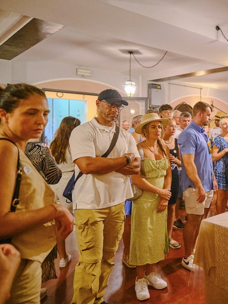 Tourists enjoying a wine tasting experience in Tuscany during a Pisa, Siena, and San Gimignano day trip.