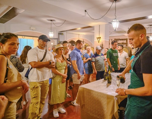 Tourists enjoying a wine tasting experience in Tuscany during a Pisa, Siena, and San Gimignano day trip.