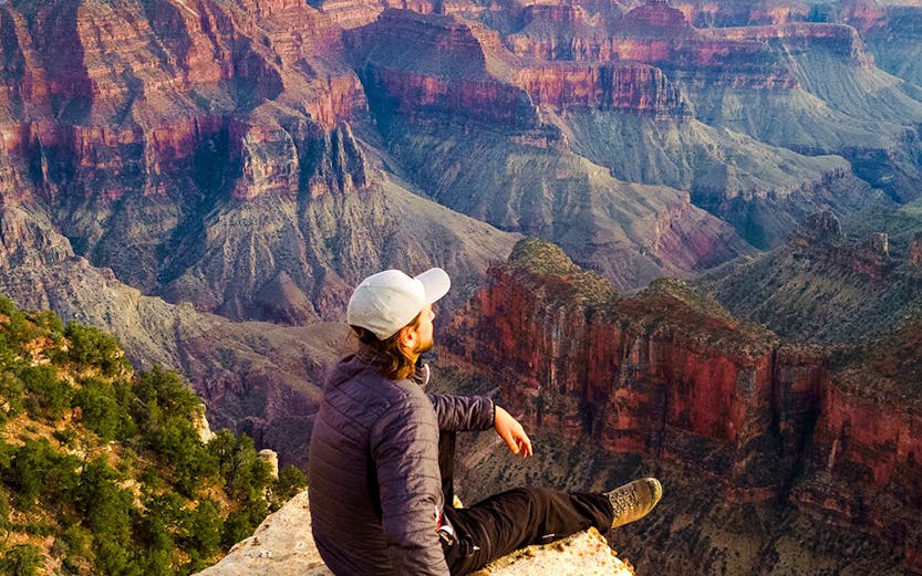 Man sitting on the edge of the Grand Canyon, Arizona, enjoying the view.