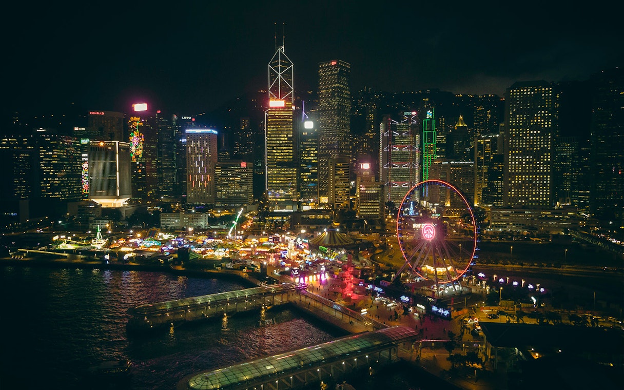 Hong Kong skyline at night with illuminated Observation Wheel and waterfront.