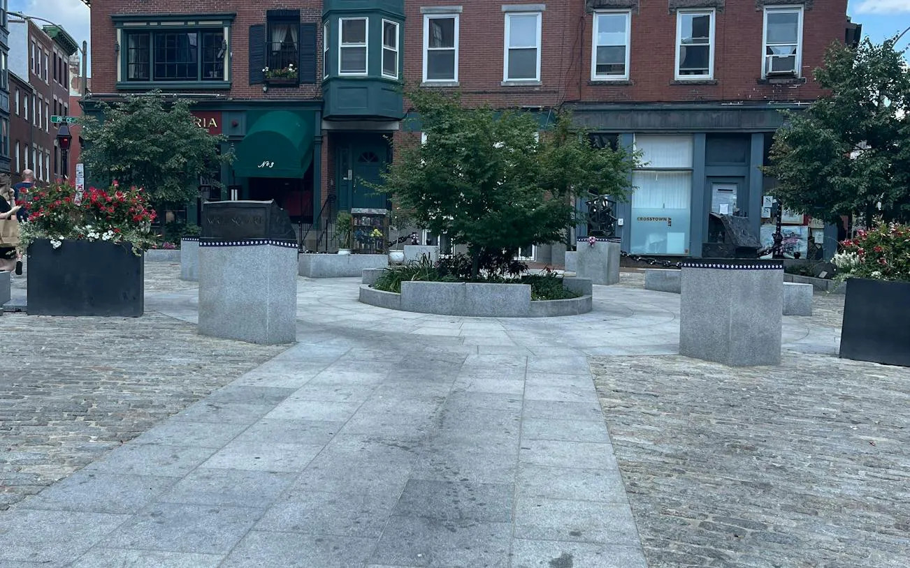 Urban square with planters and historic buildings in Boston, part of a self-guided city exploration game.