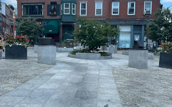 Urban square with planters and historic buildings in Boston, part of a self-guided city exploration game.