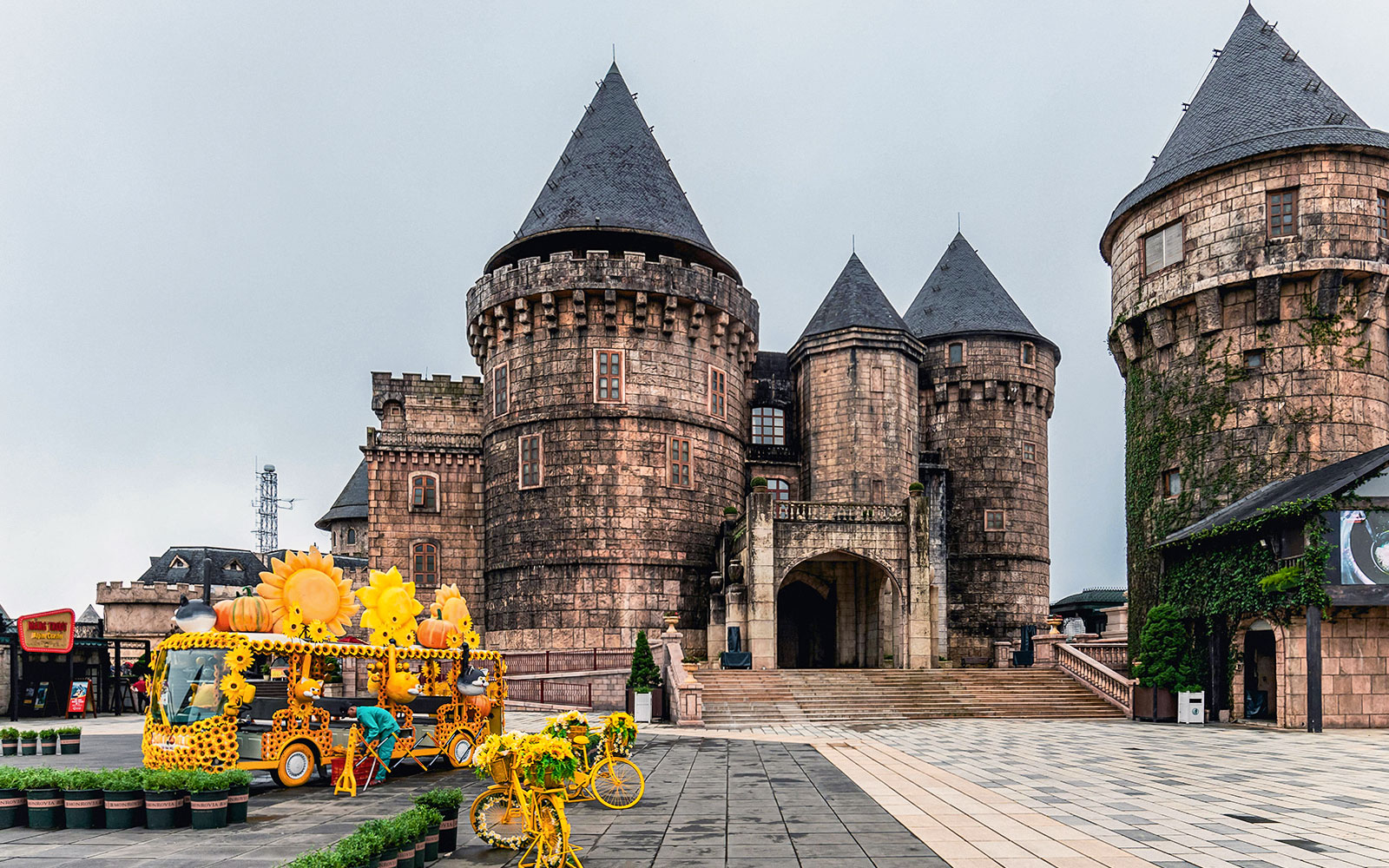 Central square in Ba Na Hills with castle towers and sunflower-themed decorations.
