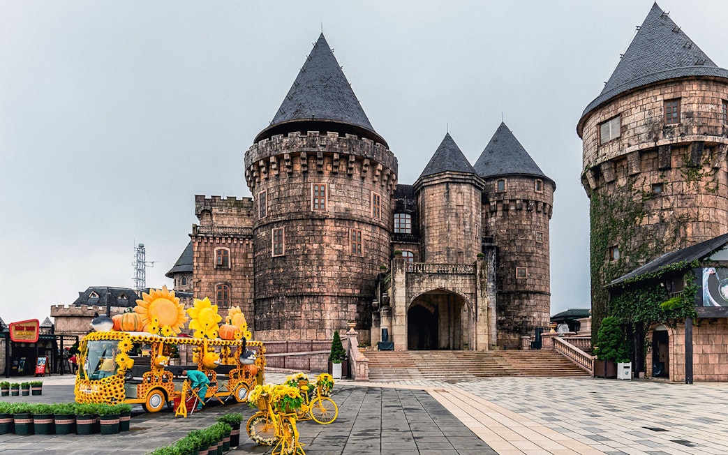 Central square in Ba Na Hills with castle towers and sunflower-themed decorations.
