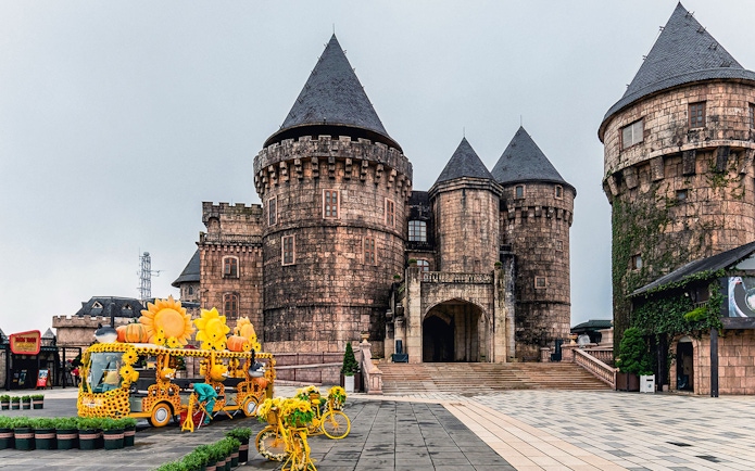 Central square in Ba Na Hills with castle towers and sunflower-themed decorations.