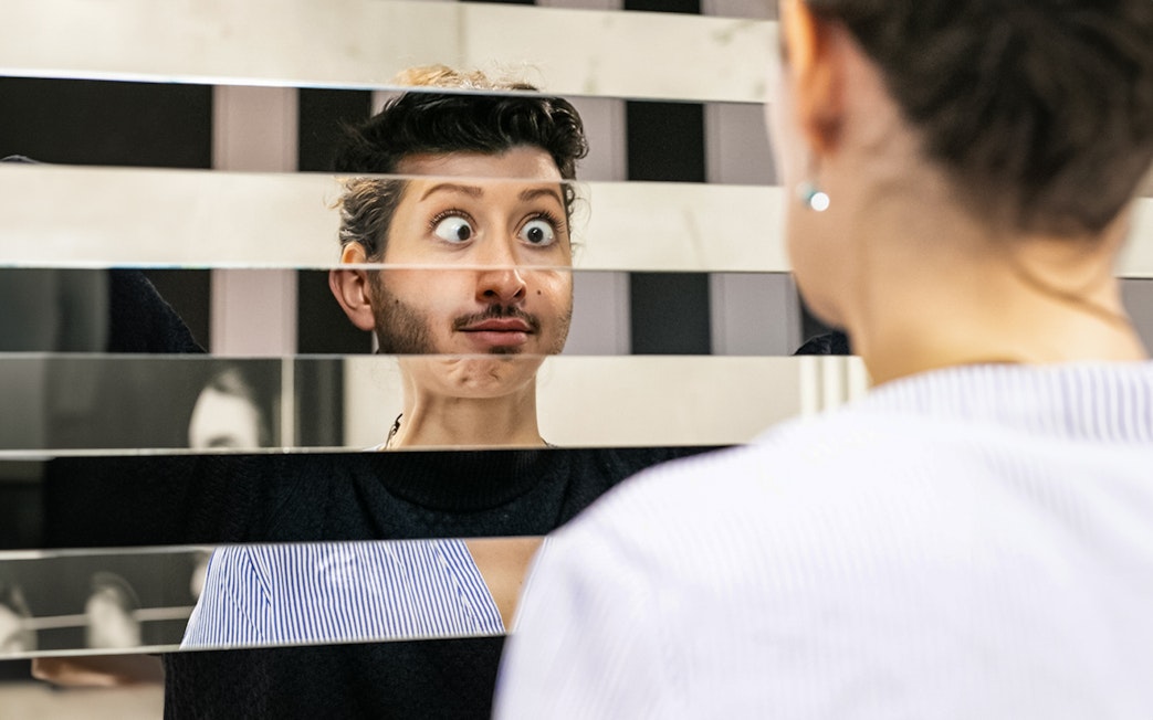 Person looking into a fragmented mirror at Illuseum Berlin.