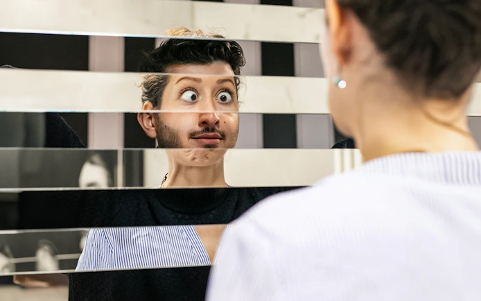 Person looking into a fragmented mirror at Illuseum Berlin.