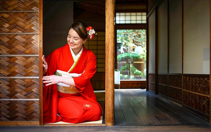 Person in kimono kneeling in traditional Kyoto machiya, preparing for tea ceremony.