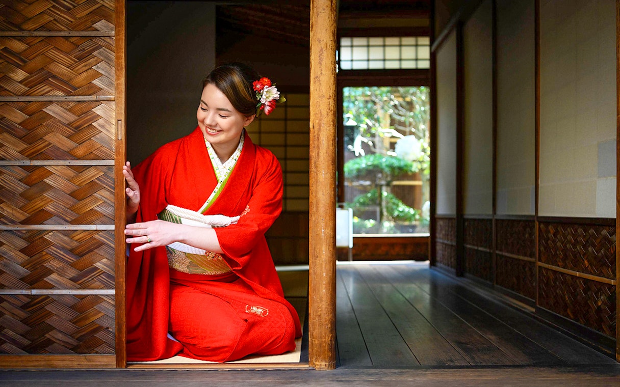 Person in kimono kneeling in traditional Kyoto machiya, preparing for tea ceremony.