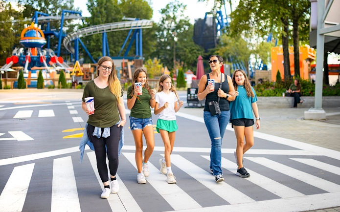 Visitors walking at Six Flags Carowinds Aeronatica Landing with rides in the background.
