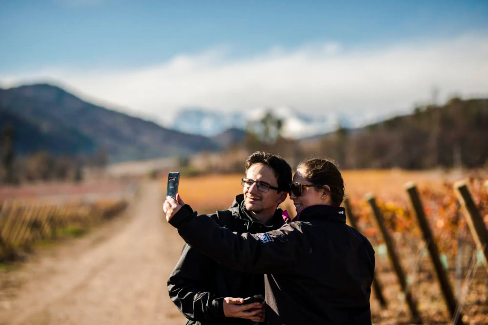 Couple taking a selfie at Santa Rita Vineyard with Andes mountains in the background, Santiago.