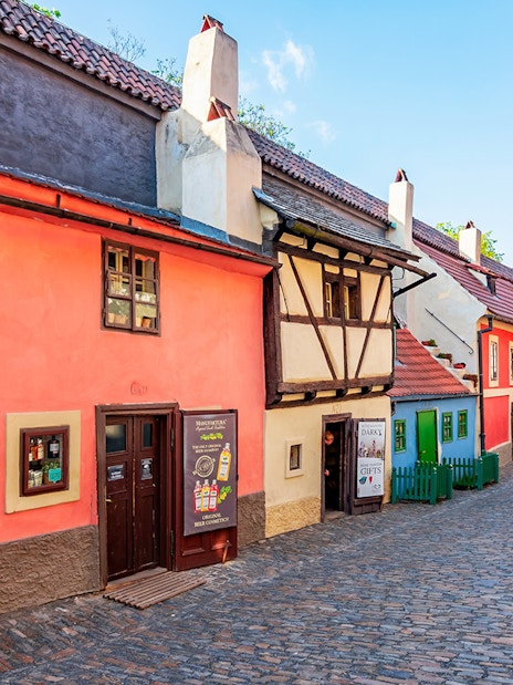 Colorful historic houses on Golden Lane, Prague, with tourists walking along the cobblestone street.