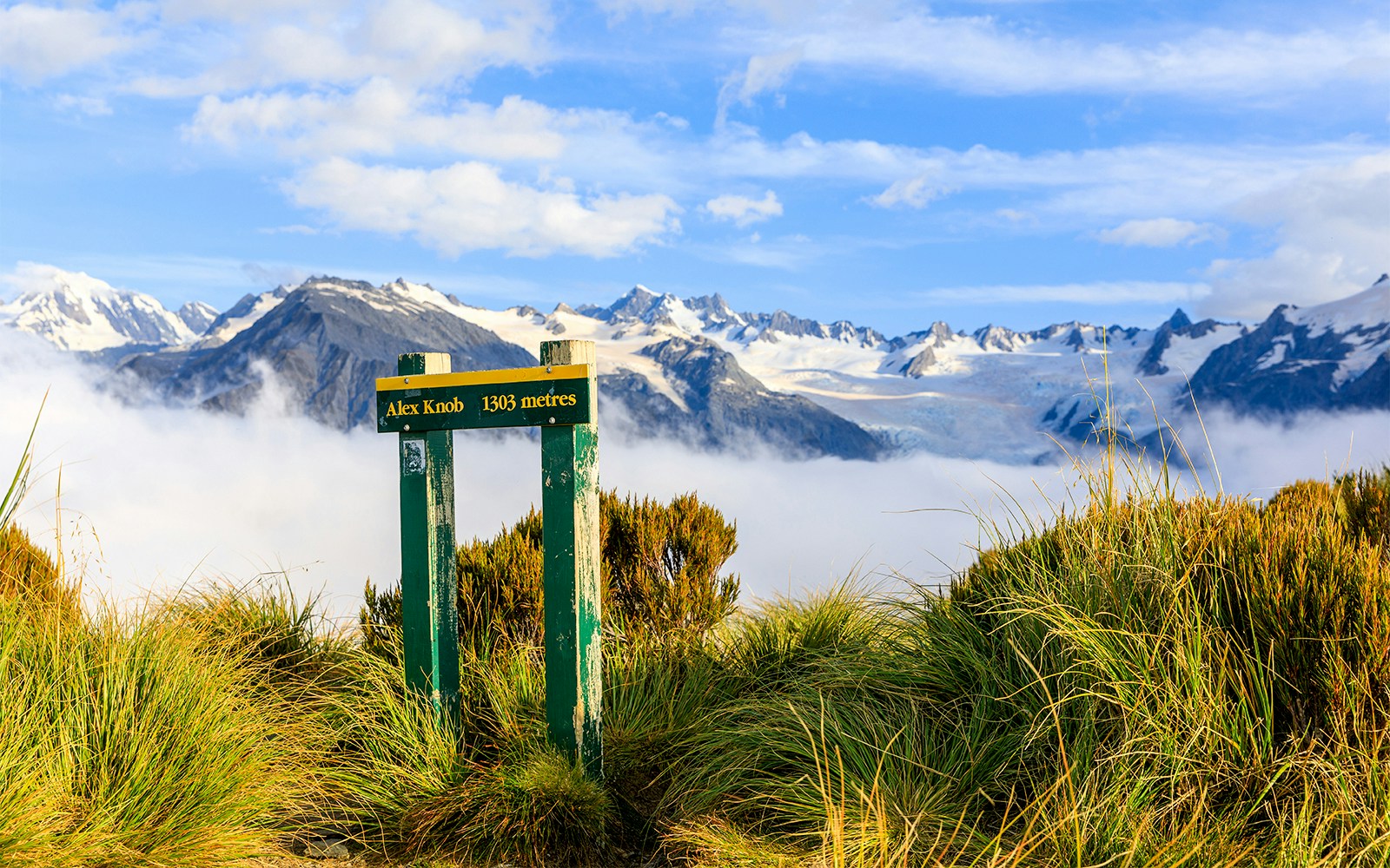 Alex Knob summit sign with Southern Alps and clouds, Franz Josef, New Zealand.