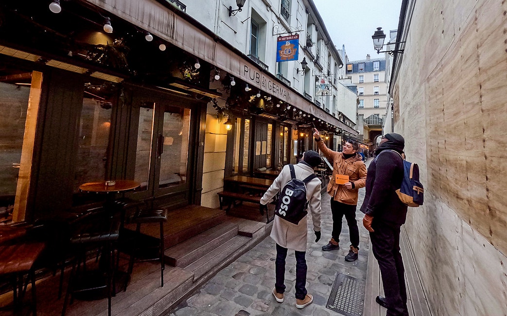 Tour guide leading a group past Pub St Germain in Saint-Germain-Des-Prés, Paris.