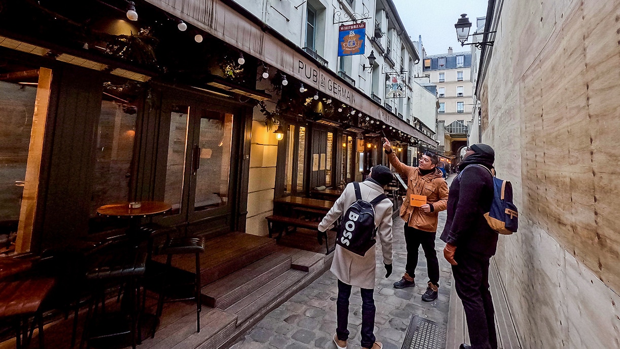 Tour guide leading a group past Pub St Germain in Saint-Germain-Des-Prés, Paris.