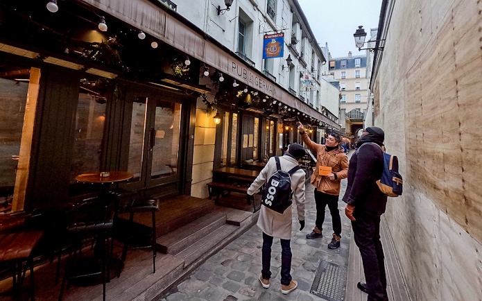 Tour guide leading a group past Pub St Germain in Saint-Germain-Des-Prés, Paris.