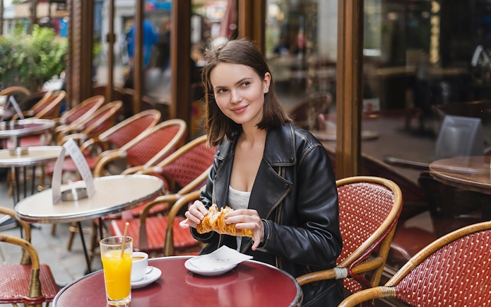 Person enjoying a croissant at a Parisian café during the Notre Dame Paris Secret Food Tour.
