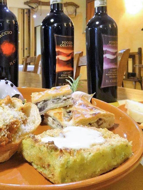Wine bottles and Italian appetizers on a table during a Pisa, Siena, San Gimignano & Chianti day trip.