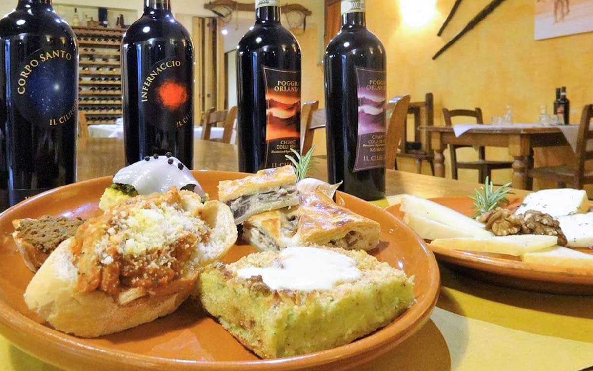 Wine bottles and Italian appetizers on a table during a Pisa, Siena, San Gimignano & Chianti day trip.