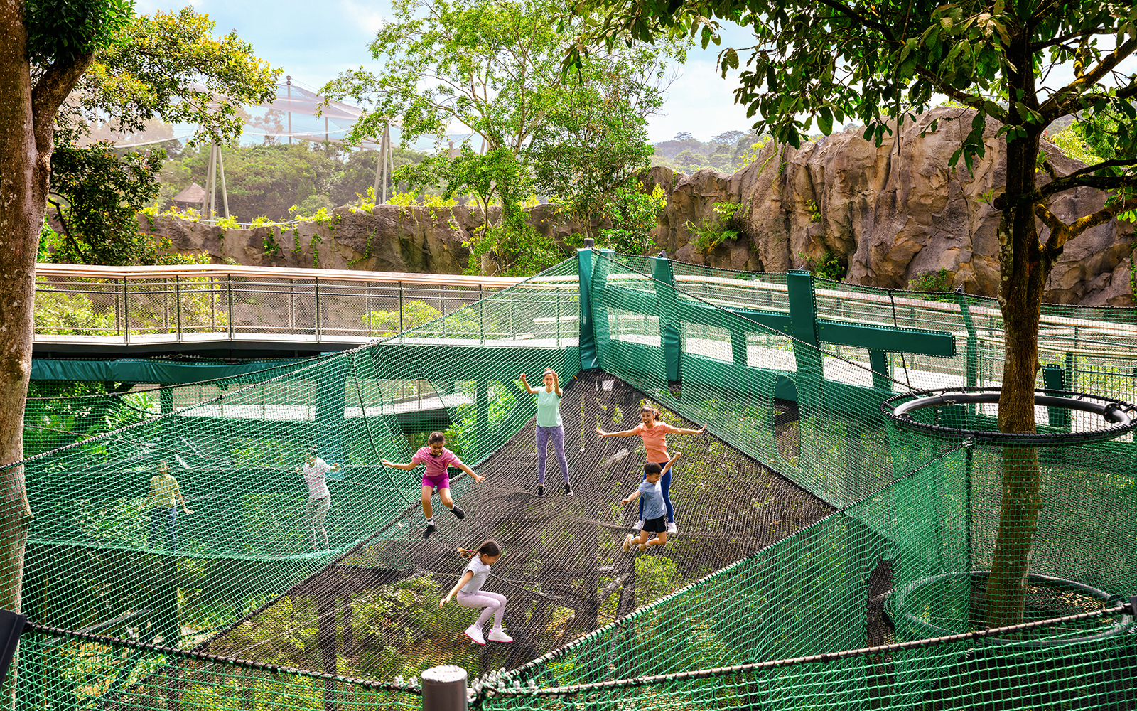 Children playing on AIA Vitality Bounce Nets surrounded by lush greenery.