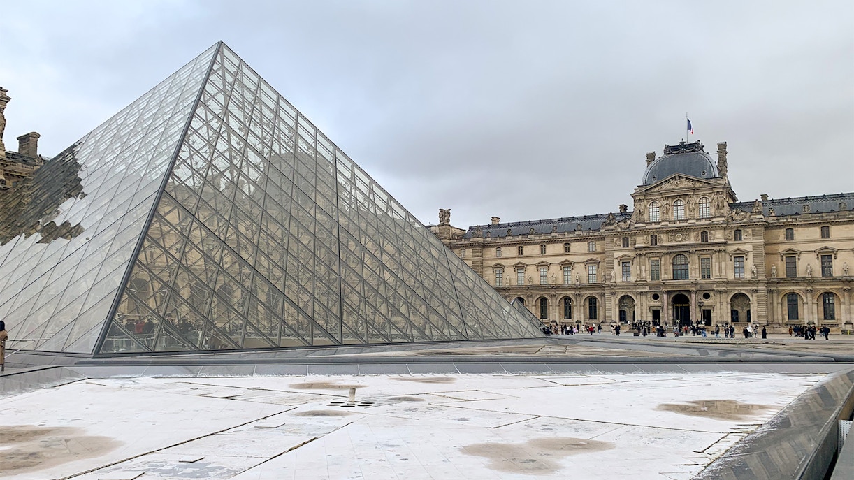 Louvre Museum tour group exploring the iconic glass pyramid entrance in Paris, France