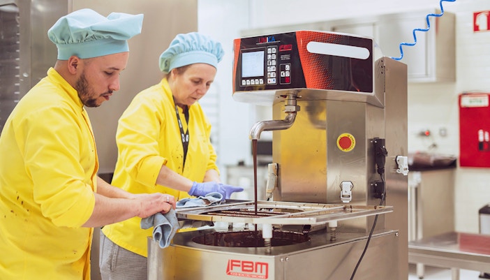 People carefully seeing the process of extracting chocolate from a machine in the Chocolate Musuem.