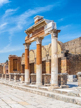 Ancient Roman columns and ruins in Pompeii, Naples under a clear blue sky.