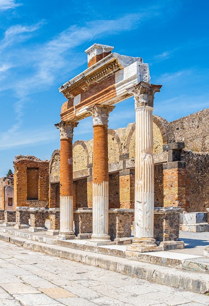 Ancient Roman columns and ruins in Pompeii, Naples under a clear blue sky.