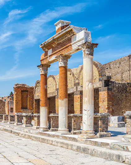 Ancient Roman columns and ruins in Pompeii, Naples under a clear blue sky.