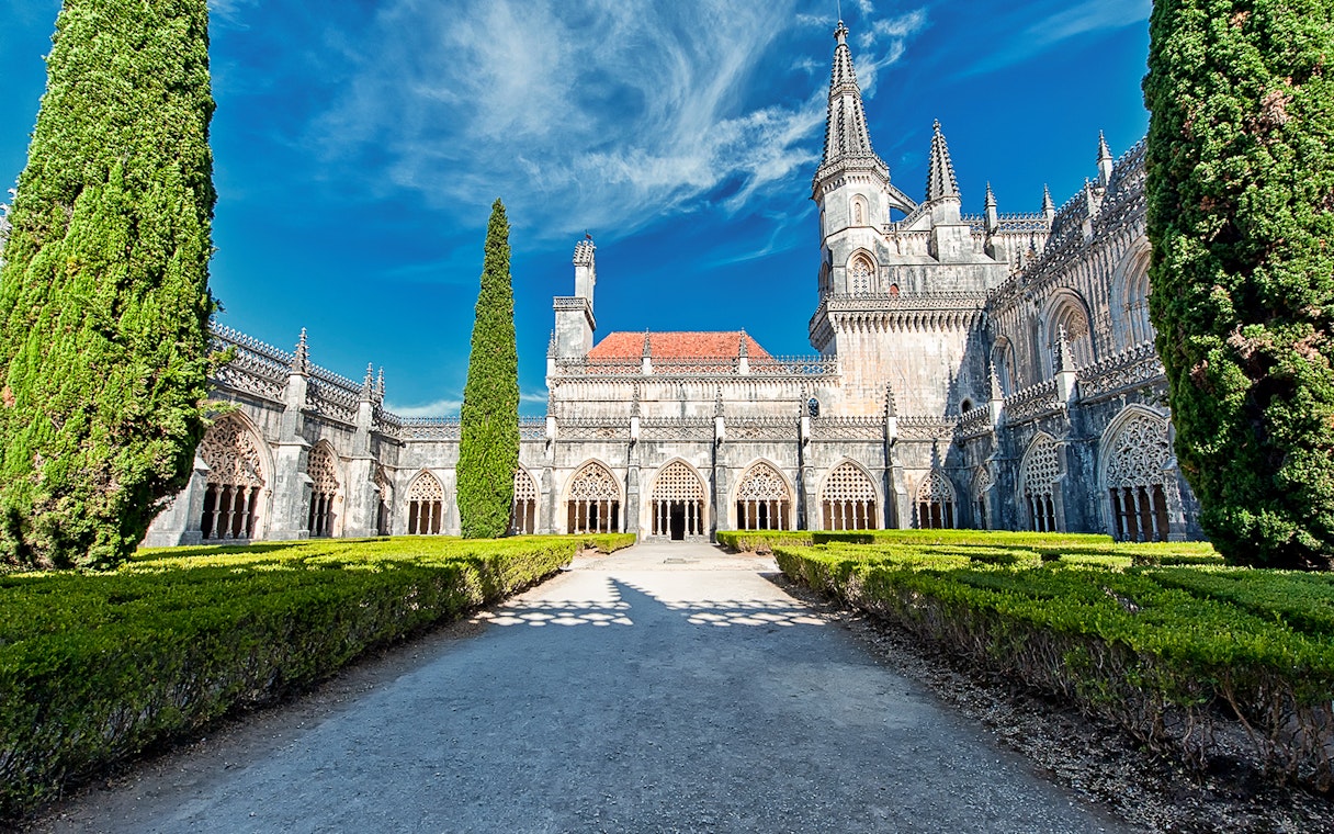 Abbey of Batalha Monastery with Gothic architecture and manicured gardens in Portugal.